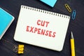 Business concept about CUT EXPENSES with sign on the piece of paper. Cost cuttingÃÂ refers to measures implemented by a company to Royalty Free Stock Photo